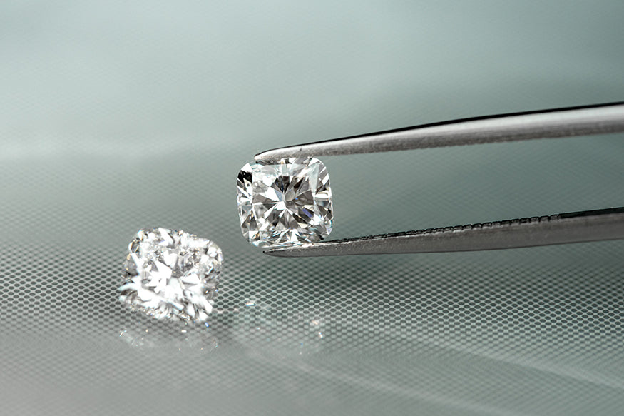 a person holding a cushion cut diamond with tweezers