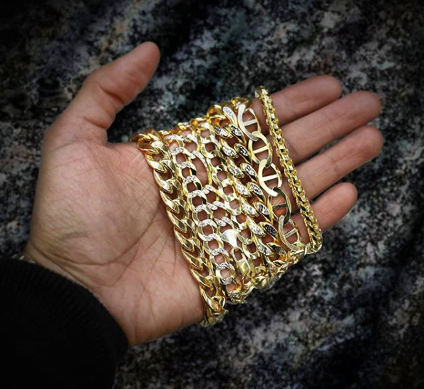 hand holding multiple gold bracelets